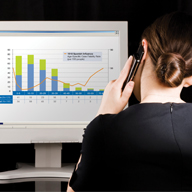 Image of a women looking at a monitor screen displaying a bar graph.